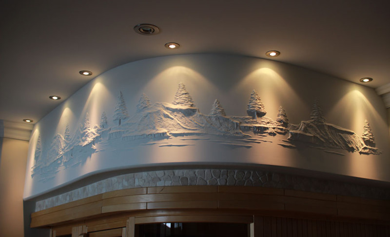 Рабочий украшает гипсокартоновые стены объемными картинами, используя лишь шпатлевку