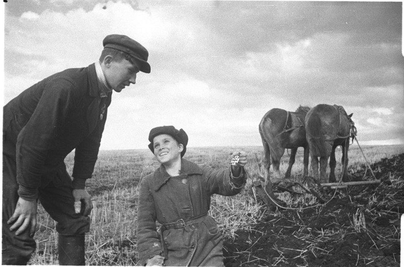 63. Советский мальчик в освобожденной деревне показывает товарищу найденный при полевых работах немецкий Железный Крест. Юго-Западный фронт.