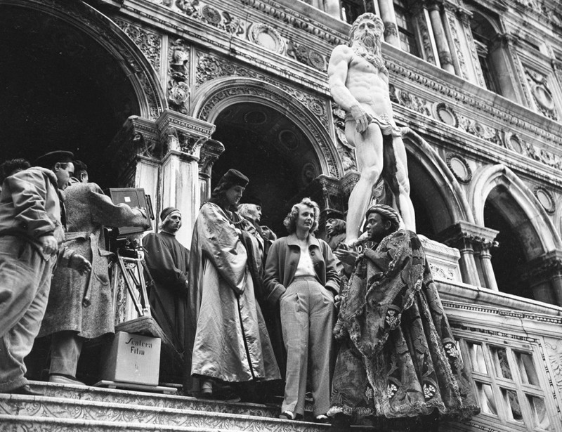 Актёр Орсон Уэллс стоит под статуей Нептуна возле Дворца дожей во время съёмок фильма «Отелло» в Венеции, Италия, 8 ноября 1949 года. Также в кадре присутствуют актёр Николас Брюс в роли Лодовико и актриса Элейн Шепард. 