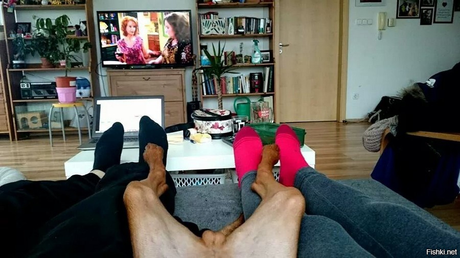 Мужчина сидит раздвинув ноги. Ноги перед телевизором. Ноги у телека.