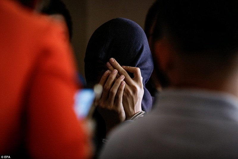 Малазиец Насир бин Мохд Uddin Hasnan, предполагаемый наркокурьер, закрывает лицо после ареста по обвинению в контрабанде кокаина  