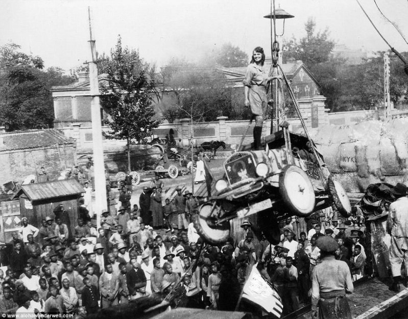 Алоха стоит на капоте своего знаменитого автомобиля Ford Model-T, который погружают на корабль, во время её тура по Африке, 1920-е годы.