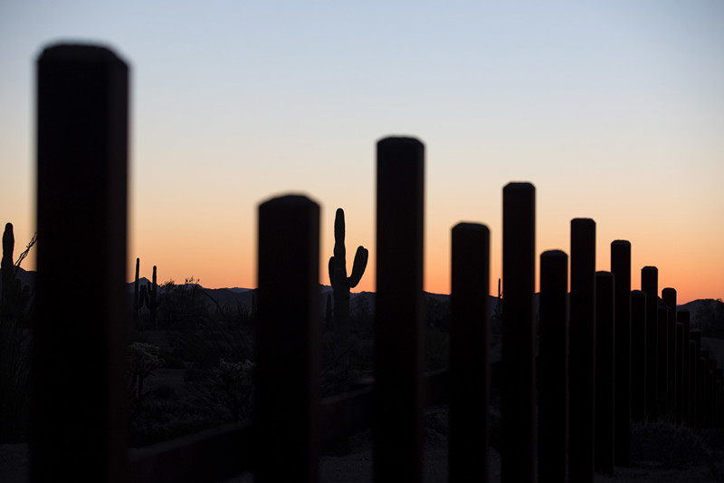 Забор и кактусы на закате, вид со стороны Мексики