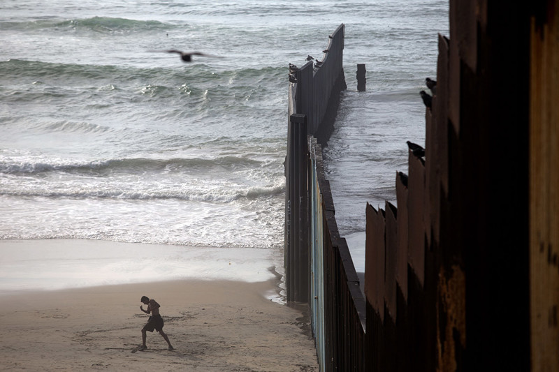 Одинокий человек разминается на пляже у самой стены в Плайяс Де Тихуана