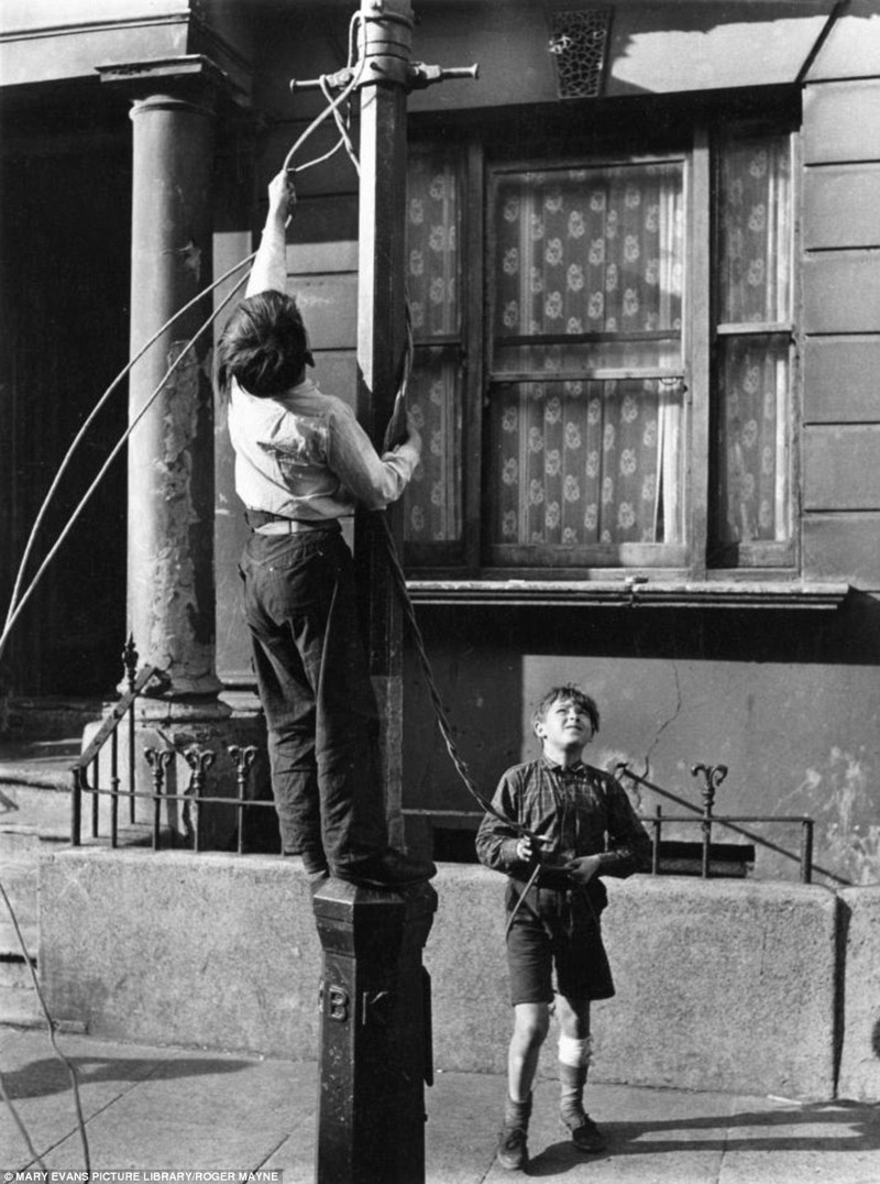 Мальчик привязывает к фонарю веревку, чтобы покататься вместе с другом, Кенсингтон, 1956 год 