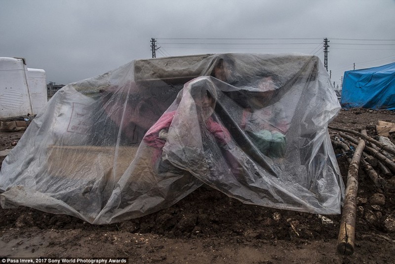 Дети-беженцы из Сирии прячутся от дождя во время транспортировки из турецкого лагеря