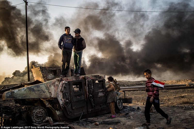 11-летний Таха Сирхах идет с иракским флагом по выжженному месторождению нефти, город Кайяра