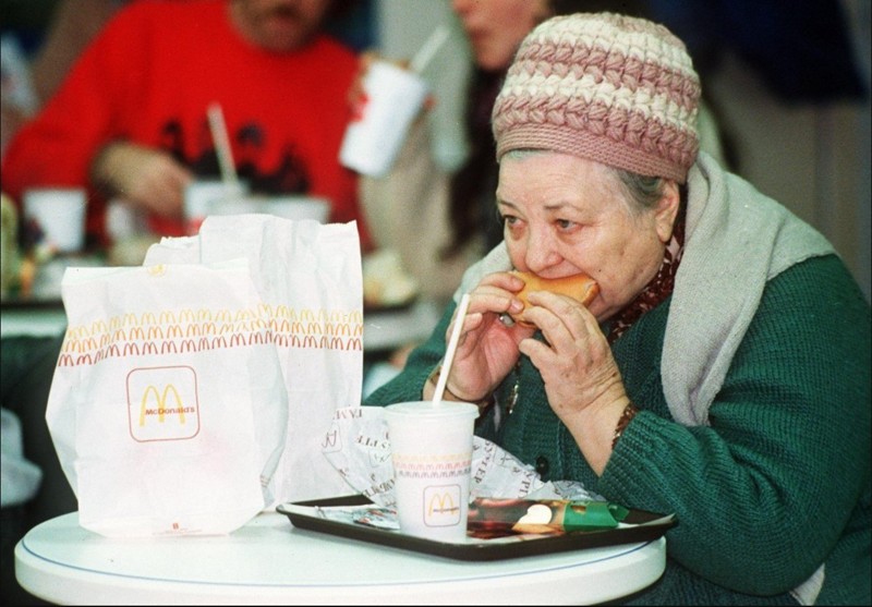 Женщина ест гамбургер в день открытия первого McDonalds, 31 января 1990 года