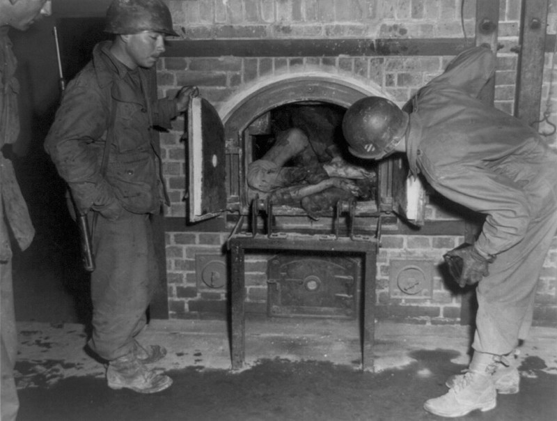 Американские  солдаты смотрят на людей в печи крематория в апреле 1945  года.