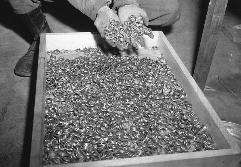 Американский  солдат осматривает тысячи золотых обручальных колец взятых у  мёртвых евреев и спрятанных в солевых шахтах Heilbronn, 3  мая 1945 года в Германии