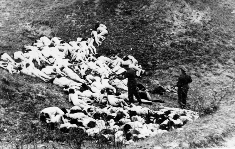 Эсэсовцы  добивают расстрелянных евреев после массового расстрела в  Mizocz, Украина. В октябре 1942 года