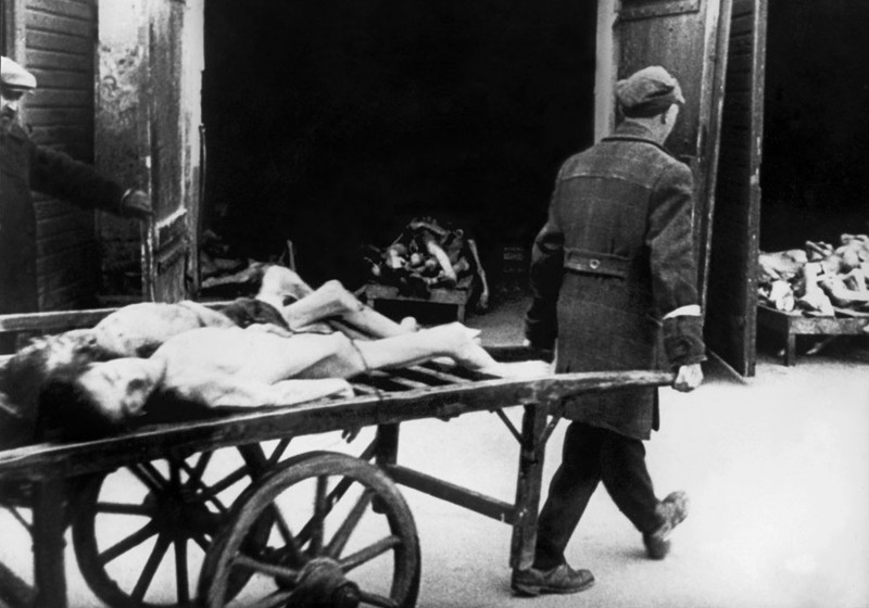 Человек уносит  тела погибших евреев в гетто в Варшаве в 1943 году, где люди  умирали от голода на улицах. Каждое утро, около 4-5 утра,  похоронные телеги собрали более десятка трупов на улицах.