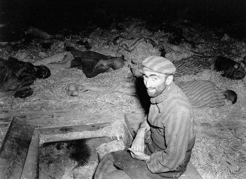 француз сидит  среди погибших в Миттельбау-Дора трудовом лагере, в  Нордхаузене, Германия, в апреле 1945 года.