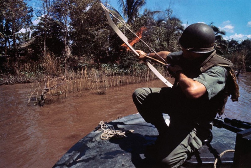 Лейтенант ВМФ США пускает горящую стрелу в хижину, которая скрывает бункер Вьетконга, Южный Вьетнам, 8 декабря 1967 года.