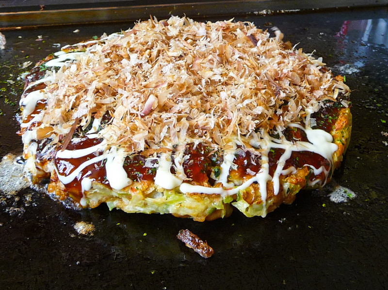 Окономияки — одно из популярнейших блюд японской уличной кухни. Это — жареная лепешка из смеси разнообразных ингредиентов, смазанная специальным соусом и посыпанная очень тонко нарезанным сушеным тунцом