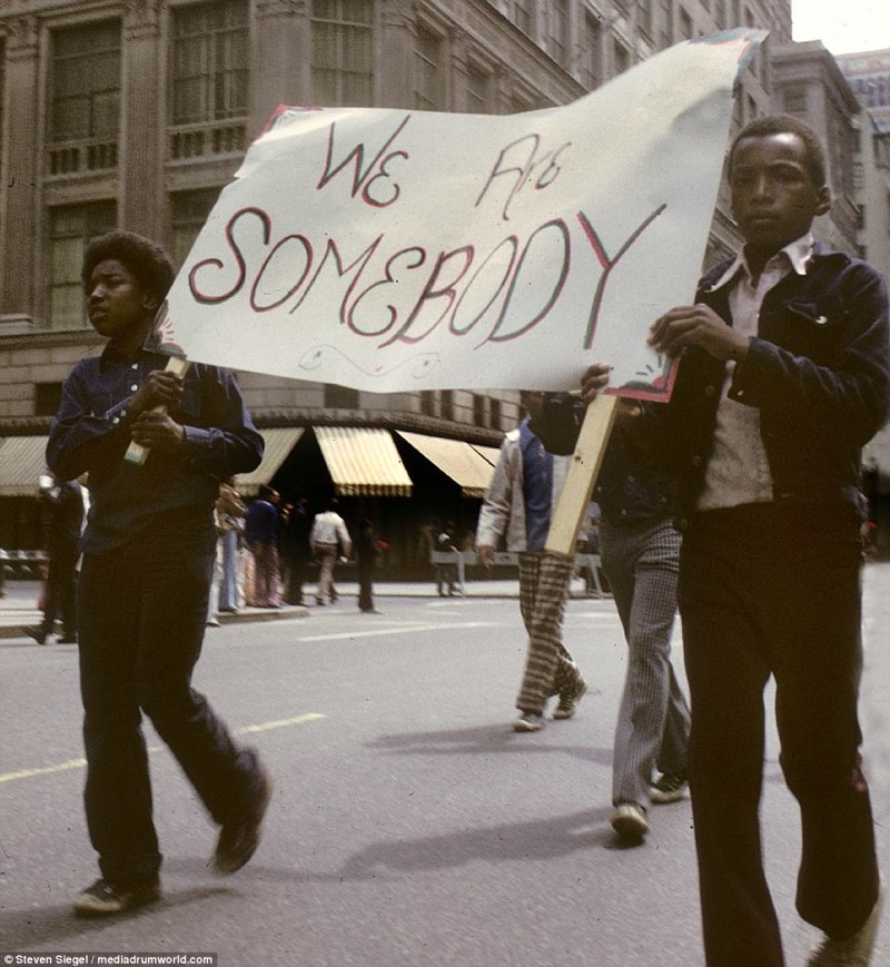 Подростки принимают участие в марше протеста, неся плакат с надписью "Мы - тоже люди" (досл. "Мы - кто-то")