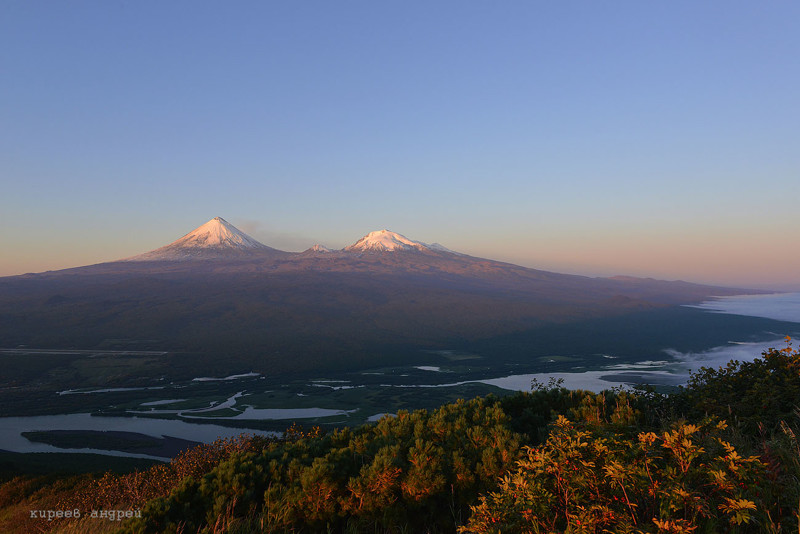 На этом снимке, если смотреть слева направо, то отчетливо виден вулкан Ключевская сопка, гора Плоская Ближняя и гора Плоская Дальняя. Внизу протекает река Камчатка.