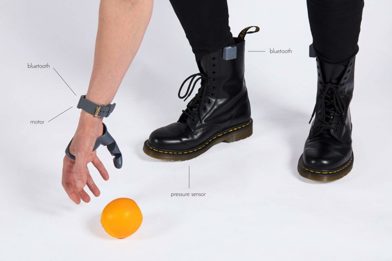 Датчики давления встроены в ботинки и с помощью Bluetooth передают сигнал, а движение пальца происходит за счет моторчика в браслете 