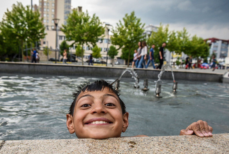 Ребенок купается в фонтане на главной площади Приштины, Косово, 14 июня 2017 года