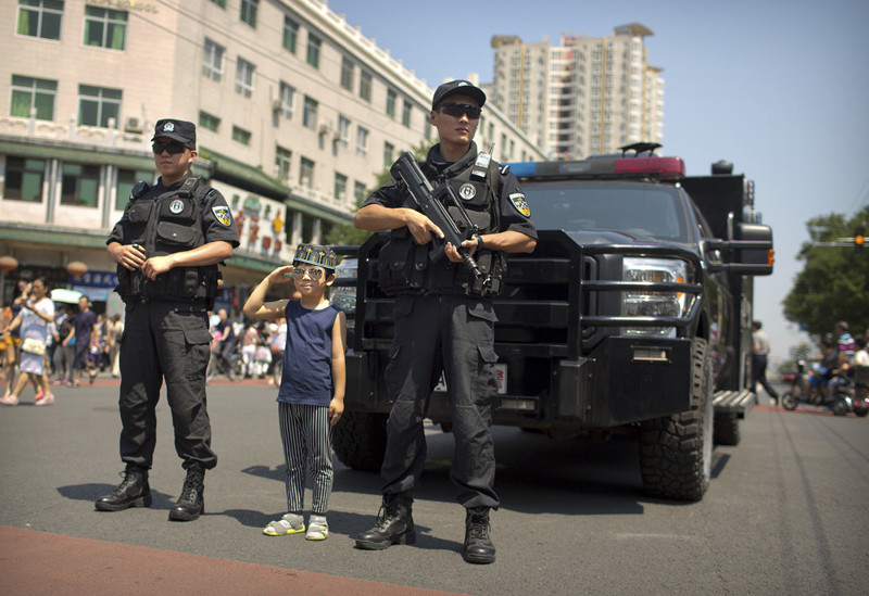 Мальчик в мусульманской тюбетейке позирует с полицейскими в Пекине, 26 июня 2017
