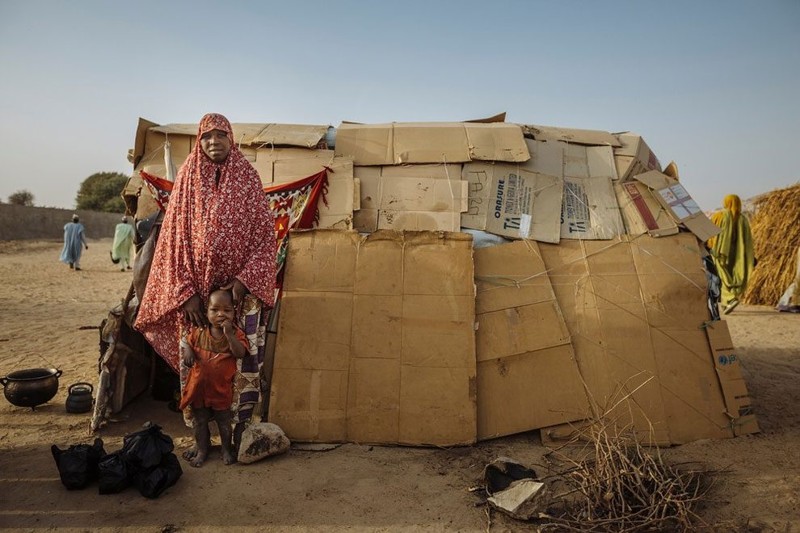 Этот дом изготовлен из картона. Сезона дождей он не выдержит, но пока женщина и ее маленький сынишка нашли здесь приют. Семья покинула свою деревню в северо-восточной Нигерии из-за атак «Боко Харам». Лагерь беженцев в Майдугури, Нигерия