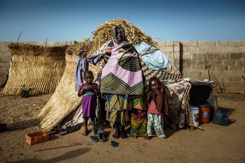 Женщина с внуками живет в маленьком доме из соломы. Лагерь беженцев в Майдугури, Нигерия