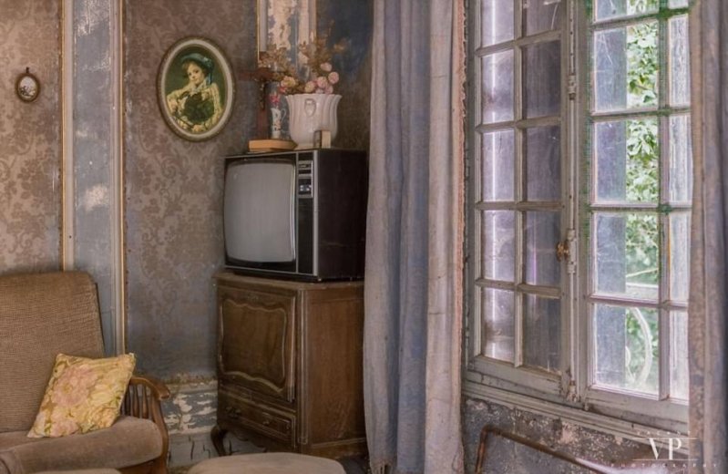 Старый телевизор стоит на шкафу в углу комнаты с обшарпанными занавесками. Этот телевизор на включали в течение почти 20 лет.