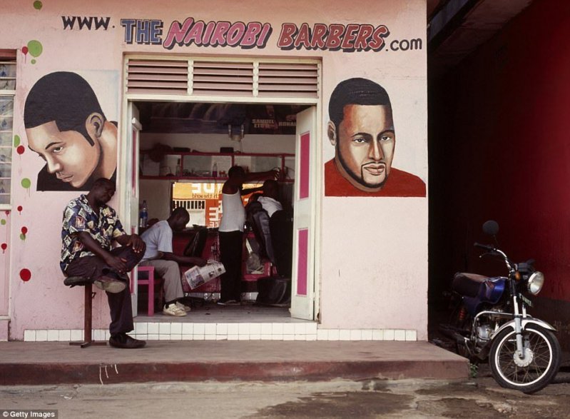 Мужчина читает газету в ожидании своей очереди в парикмахерской в Найроби, Кения.