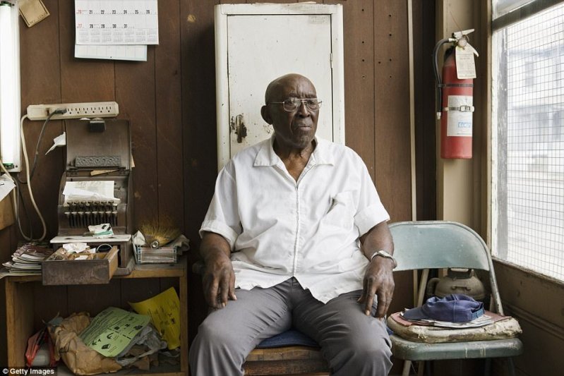 Владелец парикмахерской в Виргинии, США. На этом фото он сидит возле кассового аппарата старого образца.