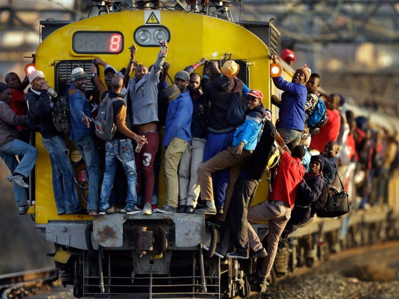 Пассажиры забрались на переполненный поезд в Соуэто в Южной Африке.