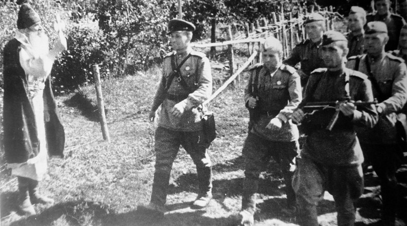 Священник осеняет крестом марширующих в колонне офицера и солдат Красной Армии. Фотография сделана предположительно в Молдавии. 1944 год.