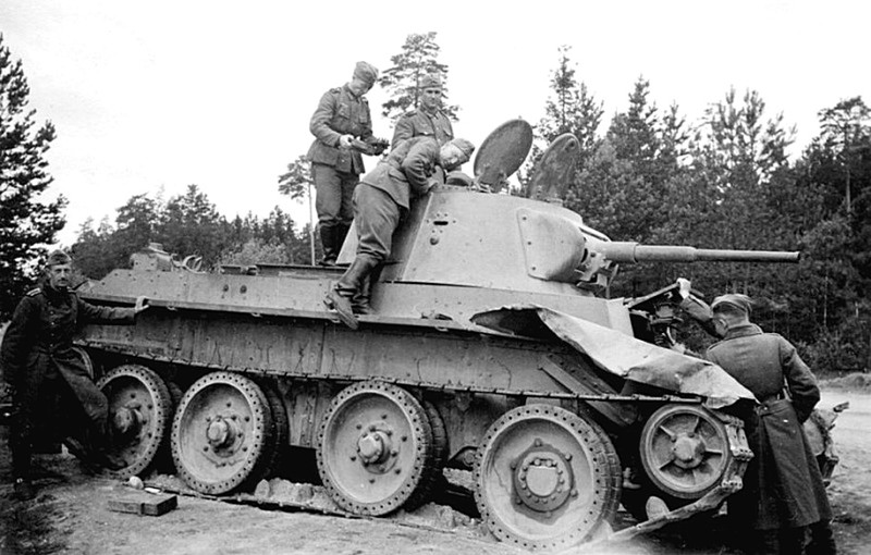 Любопытные немецкие солдаты осматривают подбитый советский легкий танк БТ-7.
