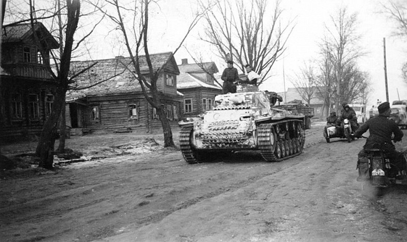 Немецкий танк Pz.Bf.Wg.III Ausf.H (командирская машина на базе модификации Pz.Kpfw. III Ausf. H) на дороге, идущей через село.