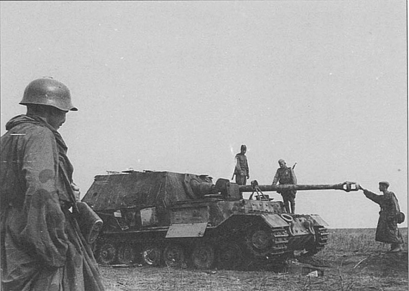 Советские солдаты осматривают подбитую в ходе Курской битвы немецкую тяжёлую самоходно-артиллерийскую установку класса истребителей танков «Фердинанд» (Ferdinand). Фото также интересно раритетным для 1943 года стальным шлемом СШ-36 на солдате слева.