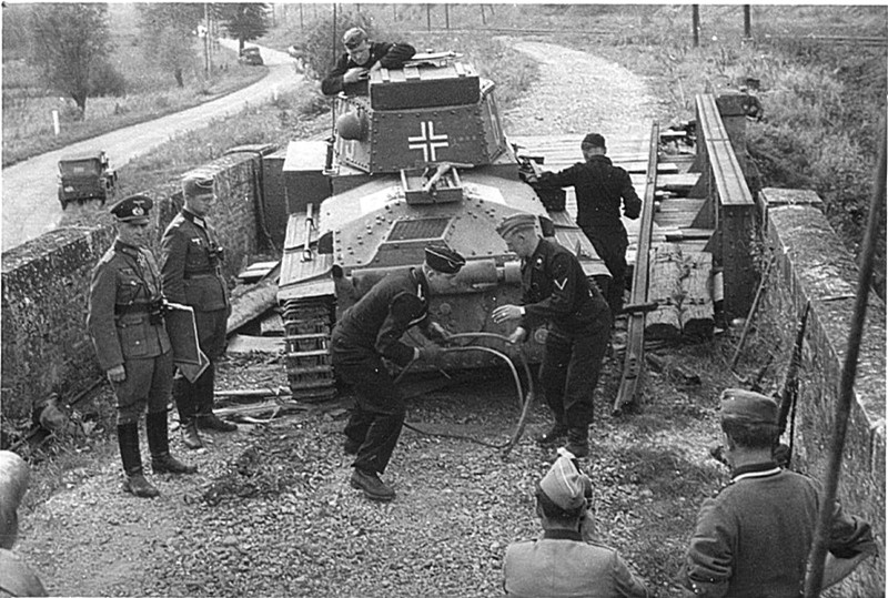 Немецкий лёгкий танк Pz.Kpfw.38(t) чешского производства из 7-й танковой дивизии потерял гусеницу при попытке преодолеть разрушенную транспортную двухуровневую развязку. На фото видно, как его готовят оттаскивать тросом с помощью другого 