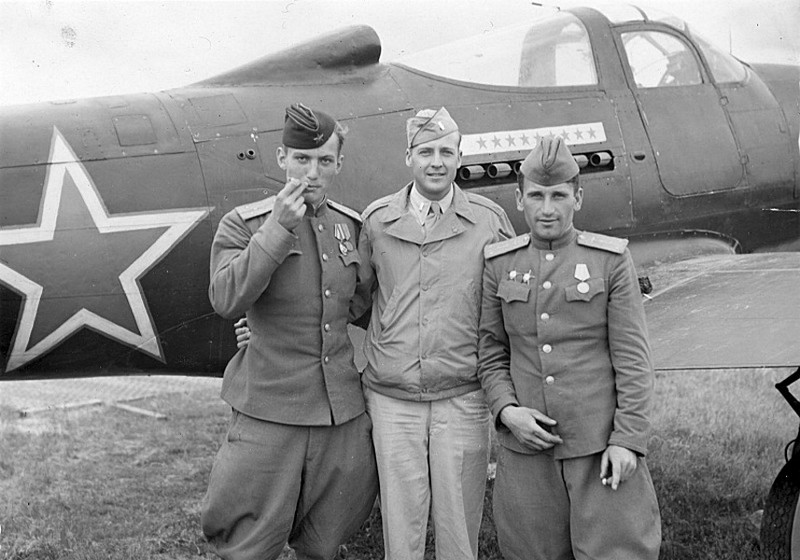 Американский и советские пилоты рядом с истребителем P-39 «Аэрокобра», поставлявшимся в СССР по ленд-лизу. Один из авиаполков Полтавского аэроузла, лето 1944 года.