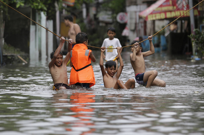 Мальчики играют возле своих затопленных домов после сильных дождей от тропического шторма “Nesat” в затопленной части Манилы, Филиппины, в четверг 27 июля 2017 года. (Photo by Aaron Favila/AP Photo)