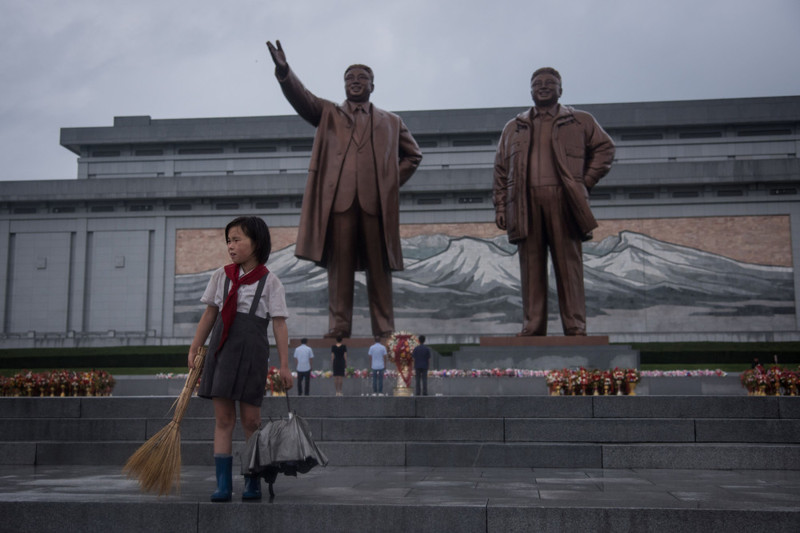 Девочка подметает возле памятника северокорейских лидеров Ким Ир Сена и Ким Чен Ира в Пхеньяне 27 июля. (Photo by Ed Jones/AFP Photo)