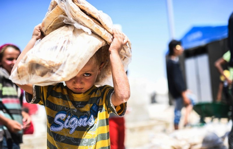 Сирийский ребенок несет хлеб во временном лагере в деревне Айн-Исса 11 июля 2017 года. (Photo by Bulent Kilic/AFP Photo)