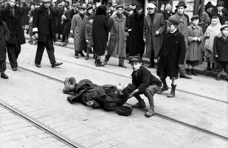 78 Ребенок держит голову молодого человека, лежащего на трамвайных рельсах — вероятно умершего от голода, Варшавское гетто, Польша, 1942 год.