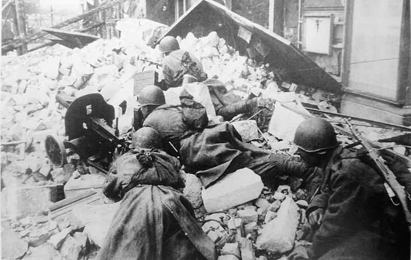 Красноармейцы с пулеметом «Максим» на груде камней на улице Берлина.