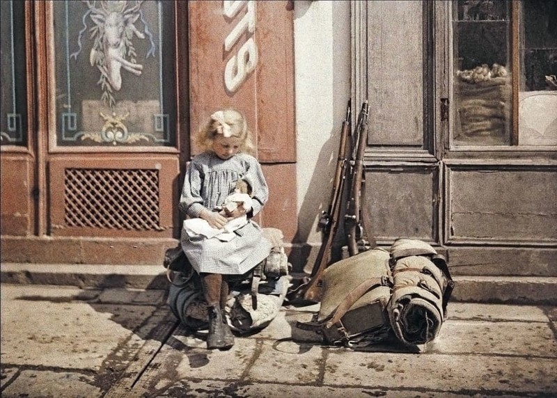 Девочка с куклой сидит на солдатском снаряжении, 1917 