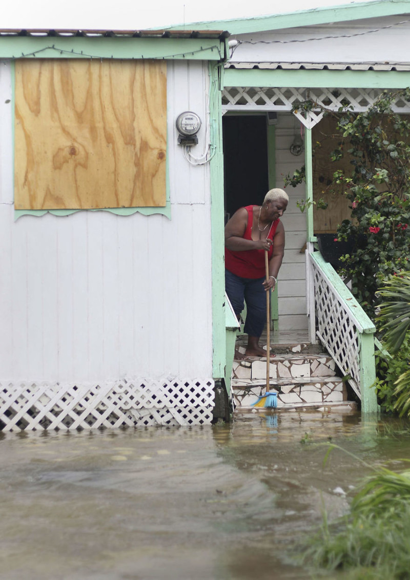 Жительница острова Антигуа выметает из дома воду после прохождения урагана Ирма
