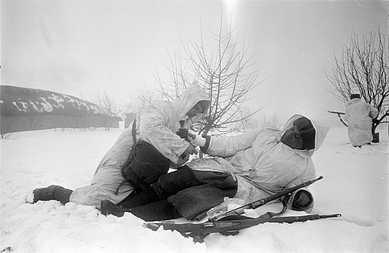Санитар перевязывает раненого в руку красноармейца во время боя на Юго-Западном фронте.
