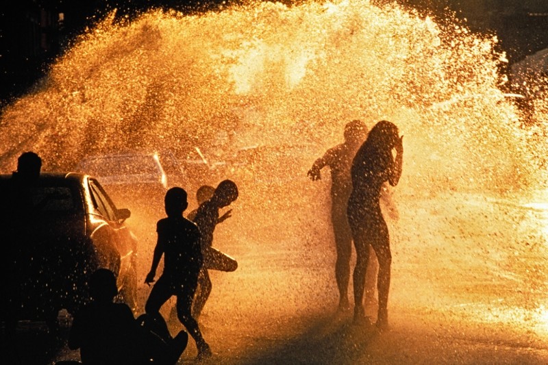 Дети играют в брызгах воды из гидранта на одной из улиц Гарлема.