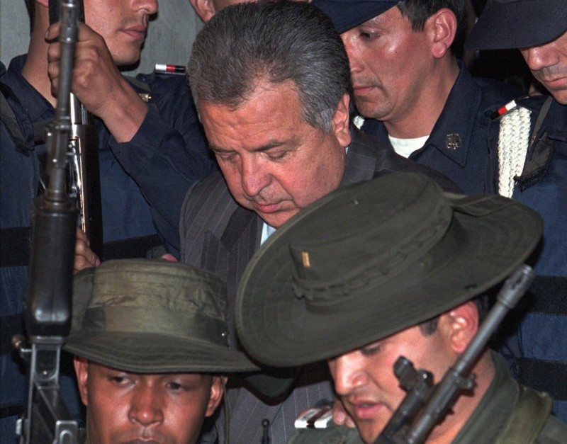 Лидер картеля Кали Хильберто Родригес Орехуэло в окружении колумбийских полицейских и тюремных охранников покидает здание Федеральной прокуратуры в Боготе, Колумбия. 6 февраля 1996 года