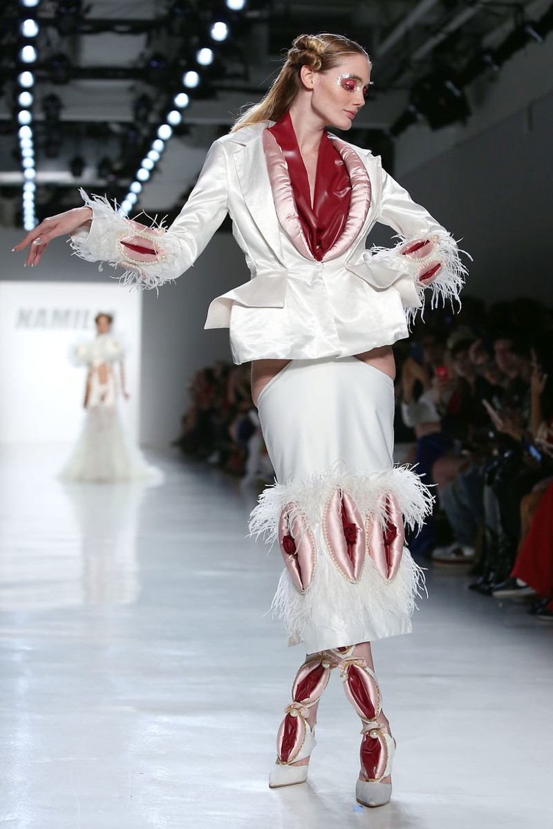 Модель демонстрирует красно-белый костюм, отделанный белым мехом