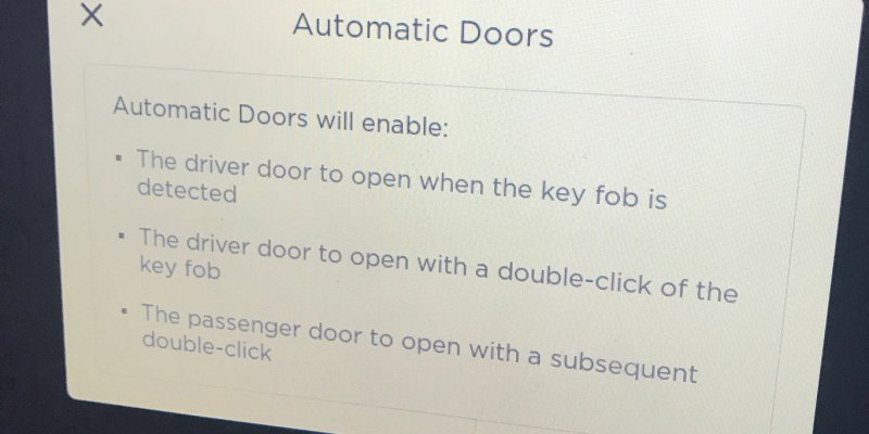 Сообщение на экране мультимедийной системы Tesla Model X, в котором говорится, что двери кроссовера открываются автоматически при приближении к машине, а также после двойного нажатия на кнопку на брелоке.