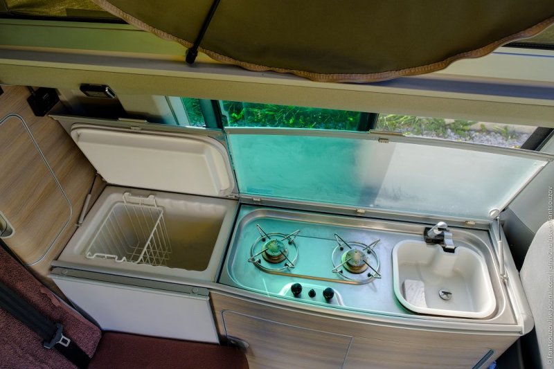 Стеклянные крышки оснащены защёлками, открываются с помощью маленьких амортизаторов. Слева холодильник с небольшой металлической корзинкой.