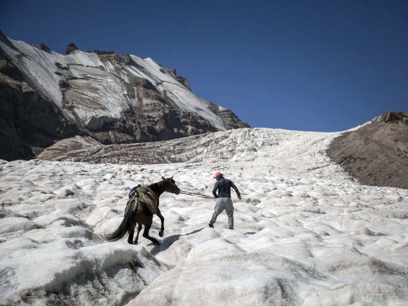 Мужчина ведёт лошадь по леднику на горе Казбек, 14 сентября 2017 года.